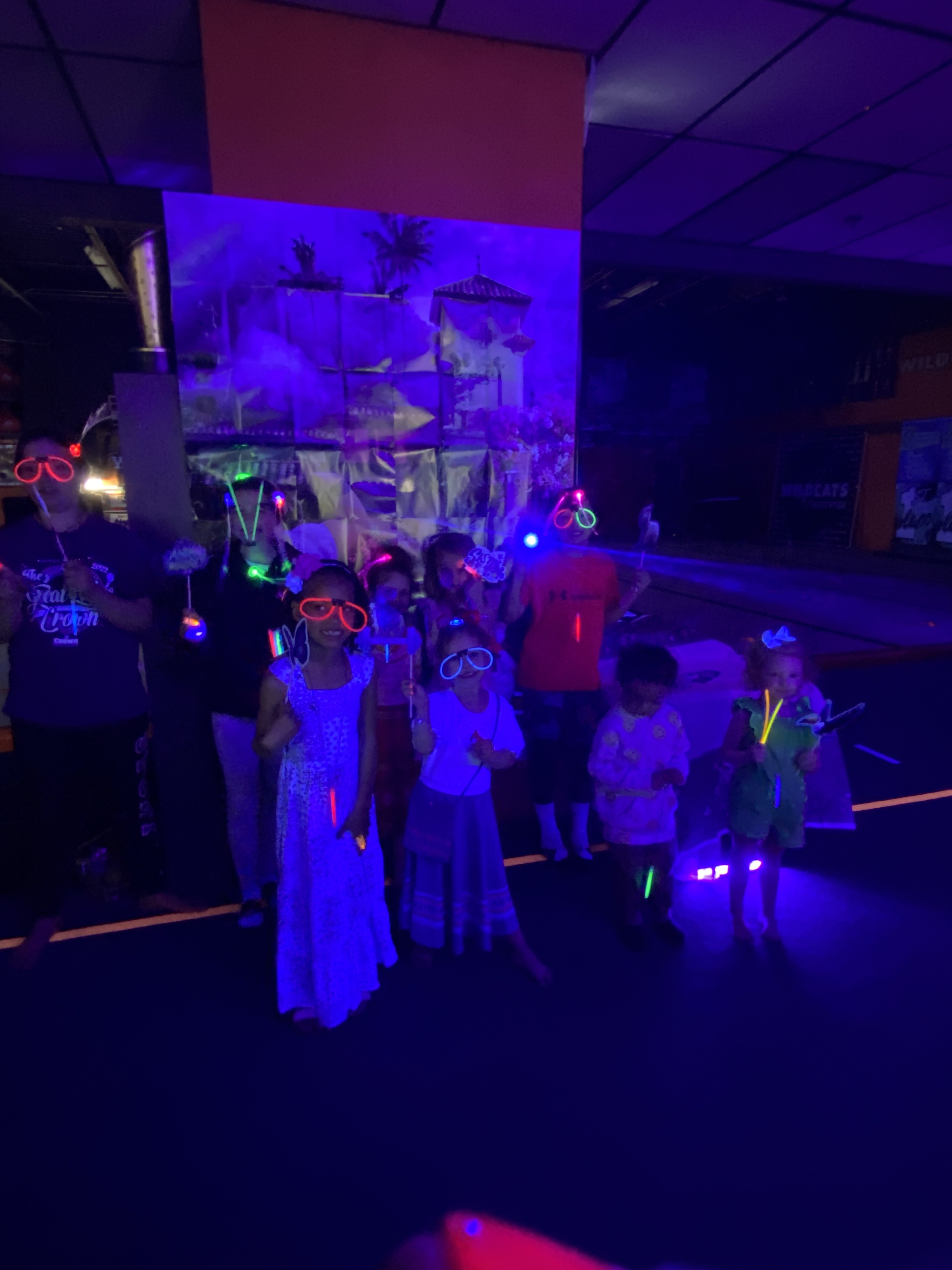 Kids posing for a picture under glow lights 