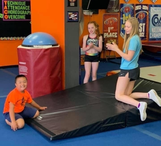 Instructor and students kneeling on tumble mat